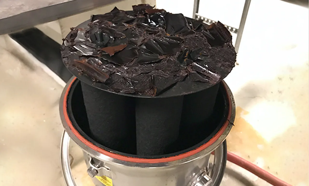 Filtermedium täckt av svart magnetit från ett värmesystem.